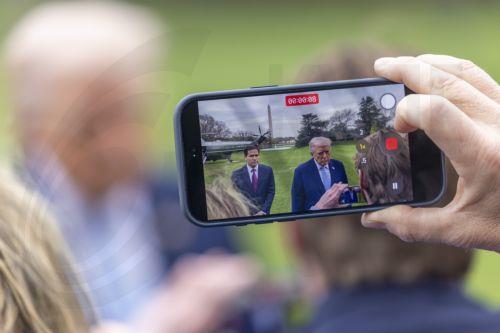 epa12837380 A person records with a phone US President Donald J. Trump responding to a question from the news media as he walks to board Marine One on the South Lawn of the White House in Washington, DC, USA, 20 March 2026.  EPA/SHAWN THEW / POOL