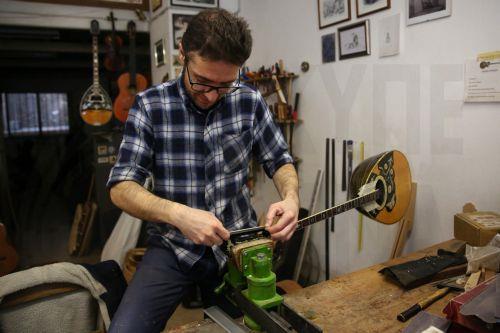 epa12838013 Panagiotis Toulikas, a maker of handmade stringed instruments, works on installing the tuning pegs upon the headstock of a bouzouki, in his workshop in Exarcheia district, Athens, Greece, 26 February 2026 (issued 21 March 2026). Panagiotis Toulikas specializes in building  guitars and bouzoukis; he believes that experienced performers prefer...