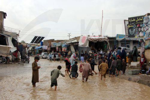 epa12851052 Residents wade through floodwaters after heavy rains in Kandahar, Afghanistan, 26 March 2026. At least ten people died and  six others were injured, while dozens of homes were destroyed and thousands of acres of farmland were severely damaged due to heavy rains and flooding in Kandahar and Helmand, according to Afghan officials.  EPA/QUDRATULLAH...
