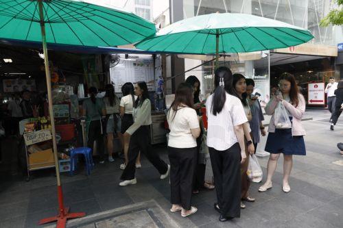 epa12859932 Thai women shield themselves from the sun under a street food vendor's umbrella during hot weather in Bangkok, Thailand, 30 March 2026. The Meteorological Department reports that Thailand is experiencing extreme heat and urges the public to avoid outdoor activity while the Digital Economy and Society Ministry warns the country's heat index is...