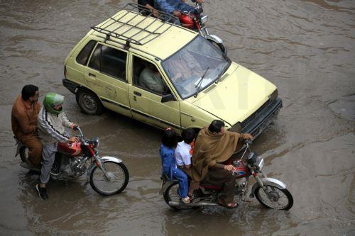 epa12860018 Vehicles drive along a flooded road during heavy rain in Peshawar, Pakistan, 30 March 2026. At least nine people were killed and several others injured after heavy rains and strong winds caused roof collapses in parts of Khyber Pakhtunkhwa and Punjab, with Bannu among the worst affected. Rescue efforts are ongoing, and authorities have warned of...