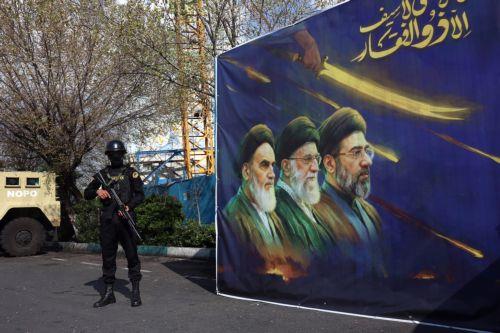 epa12861674 A member of the Iranian security forces stands guard next to a banner showing former and current Iranian supreme leaders, in Tehran, Iran, 31 March 2026. A joint US and Israeli military operation, launched on 28 February, continues to target strategic sites across Iran.  EPA/ABEDIN TAHERKENAREH