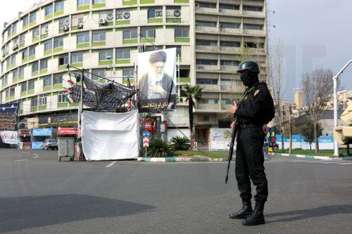 epa12861675 A member of the Iranian security forces stands guard next to a banner showing of late Iranian supreme leader Ayatollah Ali Khamenei, in Tehran, Iran, 31 March 2026. A joint US and Israeli military operation, launched on 28 February, continues to target strategic sites across Iran.  EPA/ABEDIN TAHERKENAREH