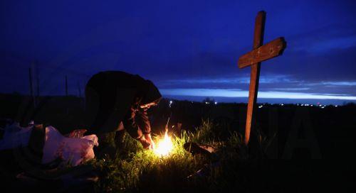 epa12876916 A woman lights a fire of dry branches at her family grave during the Orthodox Maundy Thursday memorial for the departed at a cemetery in Copaciu, Romania, 09 April 2026. Orthodox believers in the village traditionally gather in the early morning to light fires, sprinkle water and smoke over family graves, and share food in memory of their...
