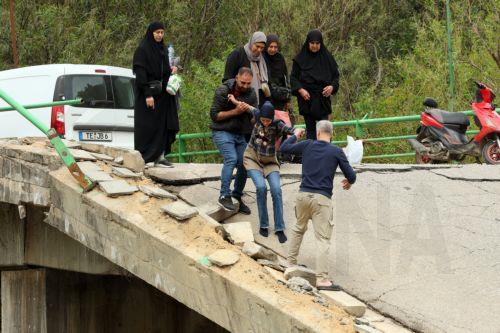 epa12900343 Displaced people walk across a destroyed bridge as they return to their villages, in the village of Tayr Felsay, in southern Lebanon, 19 April 2026. Israel and Lebanon have agreed to a 10-day ceasefire, which went into effect at midnight on 16 April.  EPA/WAEL HAMZEH