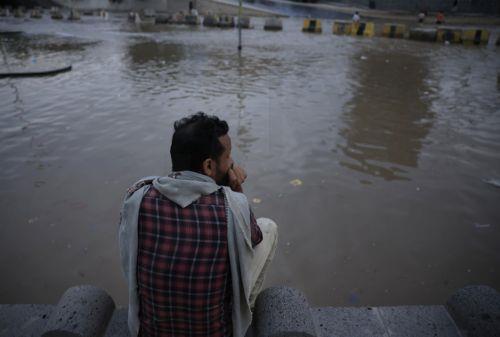 epa12929035 A person sits beside a flooded street following torrential rainfall in Sana'a, Yemen, 02 May 2026. Yemen's National Center of Meteorology and Early Warning has warned of further heavy rains and possible flooding across much of the country.  EPA/YAHYA ARHAB