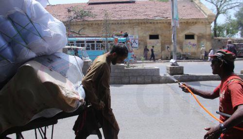epa12931535 A volunteer sprays water on people during a heatwave in Karachi, Pakistan, 04 May 2026. The Pakistan Meteorological Department has issued a heatwave alert for Karachi, warning that temperatures could rise to around 41 degrees Celsius in the coming days.  EPA/REHAN KHAN