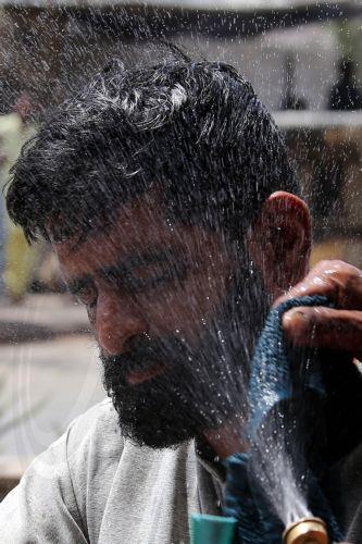 epa12931544 A volunteer sprays water on people during a heatwave in Karachi, Pakistan, 04 May 2026. The Pakistan Meteorological Department has issued a heatwave alert for Karachi, warning that temperatures could rise to around 41 degrees Celsius in the coming days.  EPA/REHAN KHAN