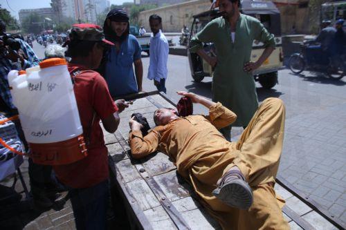 epa12931546 A volunteer sprays water on people during a heatwave in Karachi, Pakistan, 04 May 2026. The Pakistan Meteorological Department has issued a heatwave alert for Karachi, warning that temperatures could rise to around 41 degrees Celsius in the coming days.  EPA/REHAN KHAN