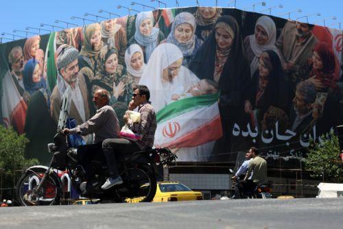 epa12992440 Iranians drive next to a huge billboard in a street in Tehran, Iran, 25 May 2026. The US and Iran voiced optimism regarding a potential peace agreement and the reopening of the Strait of Hormuz, though both sides emphasized that no such deal has been reached yet.  EPA/ABEDIN TAHERKENAREH