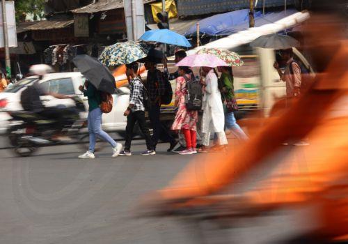 epa12994958 Indian commuters use umbrellas to protect themselves from the sun during a hot afternoon in Kolkata, India, 26 May 2026. The India Meteorological Department (IMD) has forecast temperatures to reach up to 43 degrees Celsius as a heat wave persists across West Bengal.  EPA/PIYAL ADHIKARY