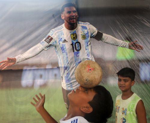 epa13032254 A young Indian ballances a ball on head near a poster of Lionel Messi of Argentina in Kolkata, india, 12 June 2026. The FIFA World Cup 2026 runs from 11 June to 19 July 2026.  EPA/PIYAL ADHIKARY