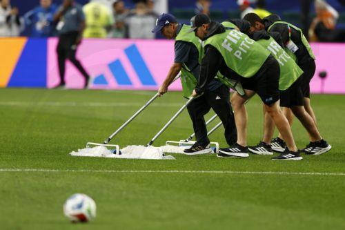 epa13057530 Stadium personeel push water off the pitch as they prepare for the match to return from suspension due to heavy rain during the FIFA World Cup 2026 group stage match France against Iraq, in Philadelphia, Pennsylvania, USA, 22 June 2026.  EPA/WILL OLIVER