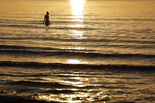 epa13060124 A swimmer during sunrise at Malvarrosa Beach after the Night of San Juan celebrations in Valencia, Spain, 24 June 2026. To welcome the summer solstice, Spain comes alive during the Night of San Juan from 23 to 24 June. The celebration features bonfires on beaches and town squares, culminating at midnight when crowds rush into the Mediterranean...