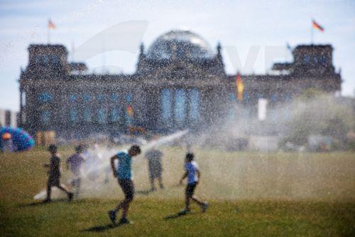 epaselect epa13060559 People are seen behind water bubbles as they move between sprinklers in front of the Reichstag building, the seat of the German parliament, during hot temperatures in Berlin, Germany, 24 June 2026. The German Weather Service forecasted strong to extreme heat stress in large parts of the country.  EPA/CLEMENS BILAN