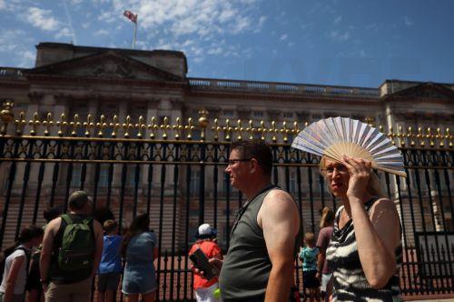 epa13066391 A woman covers her head from the sun while walking outside Buckingham Palace during hot weather in London, Britain, 26 June 2026.  The Met Office's red warning of extreme heat is still in place for the East and South East of England, as a heatwave continues to grip much of the UK.  EPA/ANDY RAIN