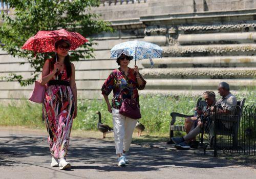 epa13098186 People shelter from the sun under umbrellas at St.James's Park in London, Britain, 08 July 2026. Amber and yellow heat-health alerts are in place across England as the UK braces for one of the longest-lasting heatwaves for fifty years. Temperatures may rise as high as 35 degrees Celsius for parts of southern England this week.  EPA/ANDY RAIN