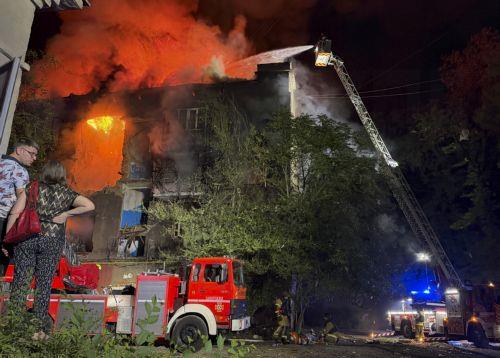 epa13108011 Local residents watch as Ukrainian rescuers work to put out the flames at the site of a Russian strike on a residential building in Zaporizhzhia, Ukraine, late 12 July 2026 (issued 13 July 2026), amid the ongoing Russian invasion. According to Zaporizhzhia Oblast Governor Ivan Fedorov, at least 13 people, including a child, were injured...