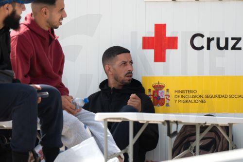 epa13130175 Newly arrived migrants wait at a Red Cross point in the port of Gran Tarajal, Fuerteventura, Spain's Canary Islands, 24 July 2026. About 20 migrants arrived on Fuerteventura island aboard a possibly stolen fishing vessel from El Aaiun, Western Sahara, according to the Civil Guard and emergency services.  EPA/CARLOS DE SAA