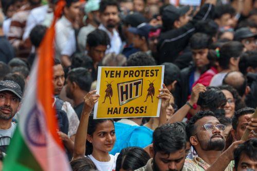epa13133543 A protester holds a placard as supporters of the youth-led satirical political movement Cockroach Janta Party (CJP) celebrate the resignation of Union Education Minister Dharmendra Pradhan, in Mumbai, India, 26 July 2026. Pradhan tendered his resignation on 25 July following nationwide student protests over examination paper leaks. ...