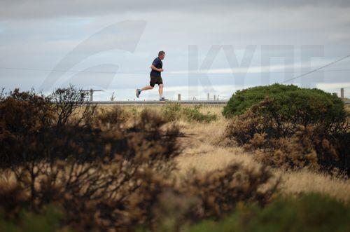 epa13135881 A jogger passes charred ground and foliage caused by Wildfires in Halkyn, Britain, 27 July 2026. A drought was declared by Natural Resources Wales in North Wales and the Upper Severn on 23 July after a prolonged period of hot, dry weather.  EPA/ADAM VAUGHAN