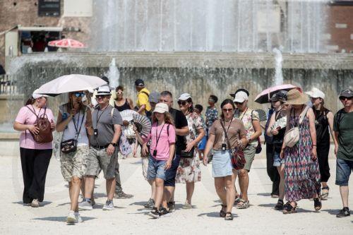 epa13143861 People use fans and shelter from the sun under umbrellas on a hot summer day in Milan, Italy, 31 July 2026. The Italian Ministry of Health issued a 'red-dot' heatwave alert for 19 cities starting 01 August. By 02 August, the number of cities under red alert is expected to increase to 23 out of the 27 being monitored.  EPA/MOURAD BALTI TOUATI