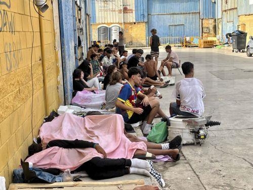epa13148248 Migrants who entered Ceuta by swimming or on foot from Morocco sit on a street in Ceuta, Spain, 03 August 2026. Surveillance along the Tarajal border, both at sea and on land, as well as new containment measures in the area, including the installation of a barrier in the sea, have reduced the number of people swimming across from Morocco to a...