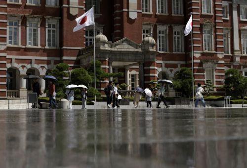 epa13155051 Passersby holding umbrellas are reflected on a water-cooling system in front of Tokyo Station, in Tokyo, Japan, 07 August 2026. Tokyo has endured a summer of persistent heat, with temperatures frequently exceeding 35 degrees Celsius, prompting authorities to issue heatstroke warnings.  EPA/FRANCK ROBICHON