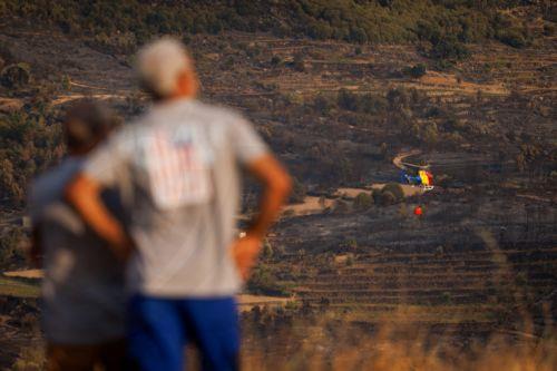 epa13176364 Local people watch the flames and smoke from a forest fire in Vilarinho da Castanheira, Portugal, 17 August 2026. The fire started in Torre de Moncorvo and spread to the municipality of Carrazeda de Ansiaes.  EPA/PEDRO SARMENTO COSTA