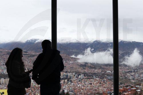 epa13177922 People look at snow-capped mountains surrounding La Paz from El Alto, Bolivia, 18 August 2026. Heavy snowfall in at least four departments forced authorities to temporarily suspend or restrict road travel on several routes to prevent accidents.  EPA/LUIS GANDARILLAS