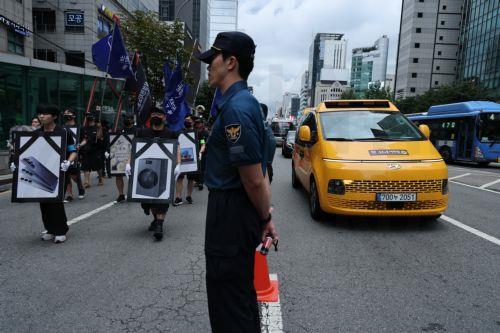 epa13182214 Samsung employees walk past police officers, standing guard, during the protest in front of Samsung Electronics’ Seocho building in Seoul, South Korea, 21 August 2026. Members of the Companion Union of Samsung Electronics (Companion Union), primarily comprised of employees from the Device eXperience (DX) division, held a rally in front of the...