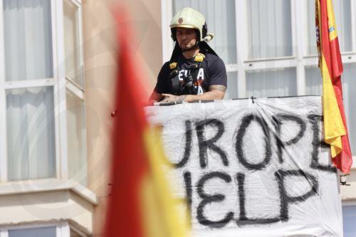 epa13202201 A firefighter protests outside a balcony during a rally called by public servants to demand more 'Resources, Means, and Solutions' amid the migrant crisis outside the offices of the Delegation of the Central Government in Ceuta, Spain, 31 August 2026. Spain faced a massive migration crisis after thousands of people crossed into the North African...