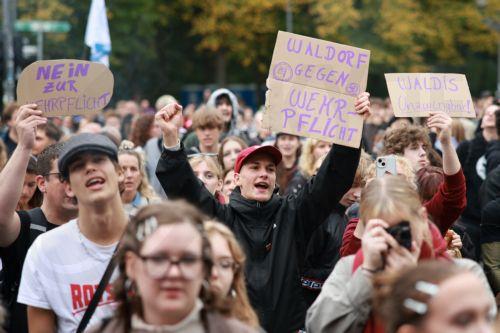 epa13277390 Participants hold placards during a protest against compulsory military service at the Brandenburg Gate in Berlin, Germany, 02 October 2026.  EPA/CLEMENS BILAN