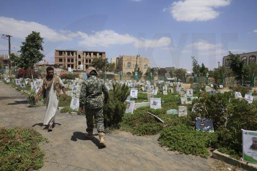 epa13277428 A Houthi soldier (R) and a person (L) walk past portraits on the graves of slain Houthi fighters at a cemetery dedicated to those who were killed in Yemen's prolonged conflict, in Sana'a, Yemen, 02 October 2026. Yemen has been at risk of rupture again amid escalating fighting along the country’s Red Sea coastal areas near the Bab al-Mandeb...