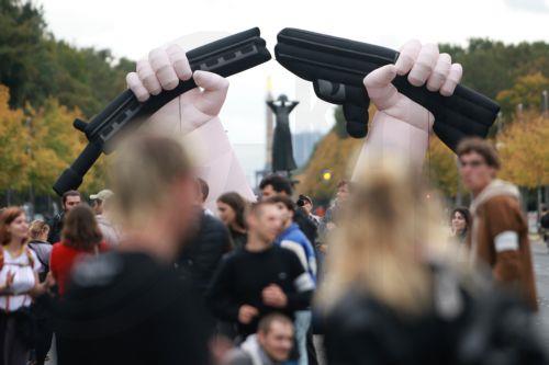 epa13277458 An inflatable installation shows hands breaking a rifle during a protest against compulsory military service at the Brandenburg Gate in Berlin, Germany, 02 October 2026.  EPA/CLEMENS BILAN