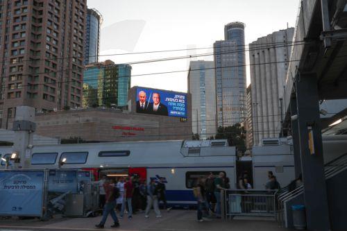 epa13283975 A large election billboard (top) shows Israeli Prime Minister Benjamin Netanyahu (C-L) and leader of the Yashar party, Gadi Eisenkot (C-R), with a message in Hebrew stating 'Netanyahu, come to a debate; what are you afraid of?' in Tel Aviv, Israel, 06 October 2026. Israel will hold elections on 27 October.  EPA/ABIR SULTAN EPA