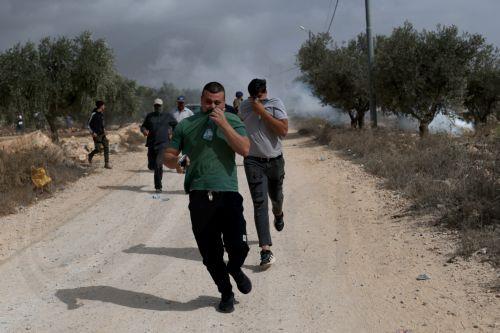 epa13309141 Palestinians run for cover from tear gas fired by the Israeli army following a settlers' attack on families harvesting their olive trees in Abu Falah, West Bank, 16 October 2026. According to Wafa, several Palestinians and a foreign journalist were injured in Israeli settler attacks on residents and olive pickers up to 3 locations in the central...