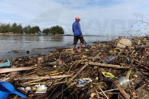 epa13333734 A man walks past a pile of plastic and wooden waste covering a riverbank in Banda Aceh, Indonesia, 27 October 2026. Plastic waste washed down from residential areas via local rivers accumulates along coastal banks before flowing into the sea.  EPA/HOTLI SIMANJUNTAK