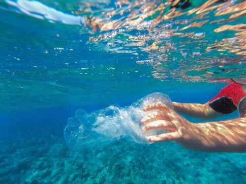 epa13339062 A person picks up a plastic bag floating beside a coral reef in the Red Sea off Marsa Alam, Egypt, 29 October 2026. Egypt generates nearly 2.9 million metric tons of plastic waste annually, according to figures published in June 2026 by Nile University researchers involved in a study for the United Nations Industrial Development Organization...