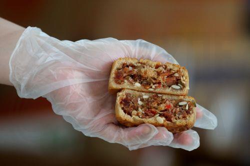 epa10139403 A worker holds a freshly baked mooncake at a bakery in Hanoi, Vietnam 26 August 2022. Mid-Autumn Festival, also known as Moon Festival, is a special festival for Vietnamese children as the celebrations involving lion dance, lantern processions and mooncakes. This year the festival falls on 10 September.  EPA/LUONG THAI LINH
