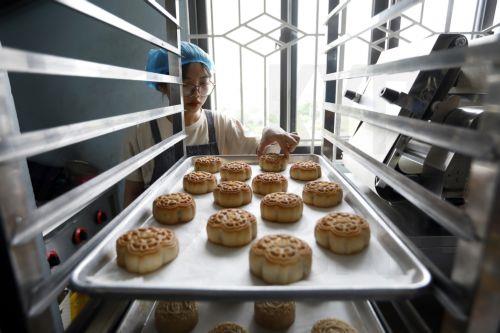 epa10139408 A worker prepares plates of unbaked mooncakes for the oven at a bakery in Hanoi, Vietnam 26 August 2022. Mid-Autumn Festival, also known as Moon Festival, is a special festival for Vietnamese children as the celebrations involving lion dance, lantern processions and mooncakes. This year the festival falls on 10 September.  EPA/LUONG THAI LINH