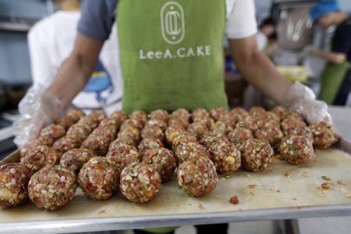 epa10139420 A worker carries a tray of mooncake fillings at a bakery in Hanoi, Vietnam 26 August 2022. Mid-Autumn Festival, also known as Moon Festival, is a special festival for Vietnamese children as the celebrations involving lion dance, lantern processions and mooncakes. This year the festival falls on 10 September.  EPA/LUONG THAI LINH