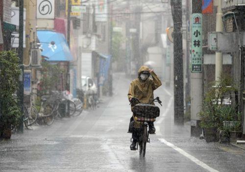 epaselect epa10194590 A woman cycles under heavy rain in Tokyo, Japan, 20 September 2022. Large typhoon Nanmadol made landfall in Kyushu on 18 September and slowly moved across Japan affecting large areas with heavy rainfalls. Latest reports say 2 people died and more than 100 are injured.  EPA/FRANCK ROBICHON