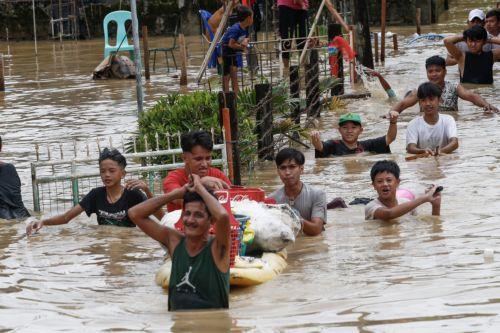 epa10206722 Residents wade through flood water caused by typhoon Noru in San Miguel town of Bulacan province, north of Manila, Philippines 26 September 2022. Typhoon Noru crossed the northern Philippine region of Luzon on 25 September and prompted thousands to evacuate due to heavy rain and strong winds. Typhoon Noru is expected to leave the Philippine area...