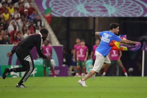 epa10335301 A steward (L) chases a pitch invader during the FIFA World Cup 2022 group H soccer match between Portugal and Uruguay at Lusail Stadium in Lusail, Qatar, 28 November 2022.  EPA/Abir Sultan