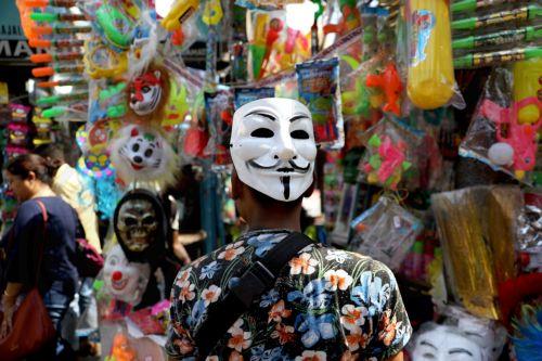 epa10500092 A vendor wears a Guy Fawkes mask from the graphic novel 'V for Vendetta' as he sells party items and colored powders ahead of the Holi celebrations in Kolkata, India, 03 March 2023. Holi, also known as the Festival Of Colors, is an ancient Indian Hindu festival symbolizing the victory of good over evil and marking the arrival of spring. It is...