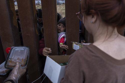 epa10624291 A migrant child held by its mother reaches out for food during a food distribution by volunteers in the no man's land between the US and Mexico, in San Diego, California, USA, 12 May 2023. According to humanitarian volunteers, there are about 400 migrants, all families, held in the no man's land between Tijuana and San Diego after crossing the...