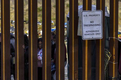 epaselect epa10624311 Migrants look on through the wall from the no man's land between the USA and Mexico next to a sign reading 'U.S. Property No Trespassing Authorized Vehicles Only', in San Diego, California, USA, 12 May 2023. According to humanitarian volunteers, there are about 400 migrants, all families, held in the no man's land between Tijuana and...