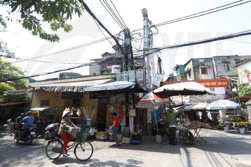 epa10630578 A woman rides a bicycle past utility poles with power cables in a street in Hanoi, Vietnam, 16 May 2023. Northern Vietnam is facing electricity shortages due to high demands amid the hot season, and decreased hydropower production, according to a report recently from Vietnam Electricity.  EPA/LUONG THAI LINH