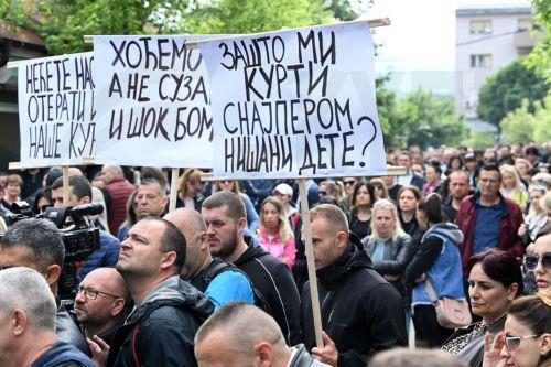 epa10668201 A man holds a banner reading in Serbian "Why is Kurti targeting my child with a sniper" during a protest in front of the municipality building in Zvecan, Kosovo, 02 June 2023. At least thirty KFOR peacekeepers and fifty two civilians were injured in clashes between security forces and ethnic Serbs in Zvecan on 29 May 2023. Tensions continue in...